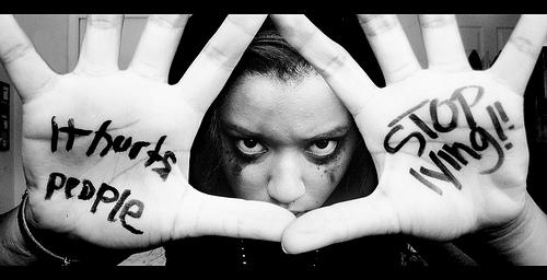 Girl with stop lying written on her palms